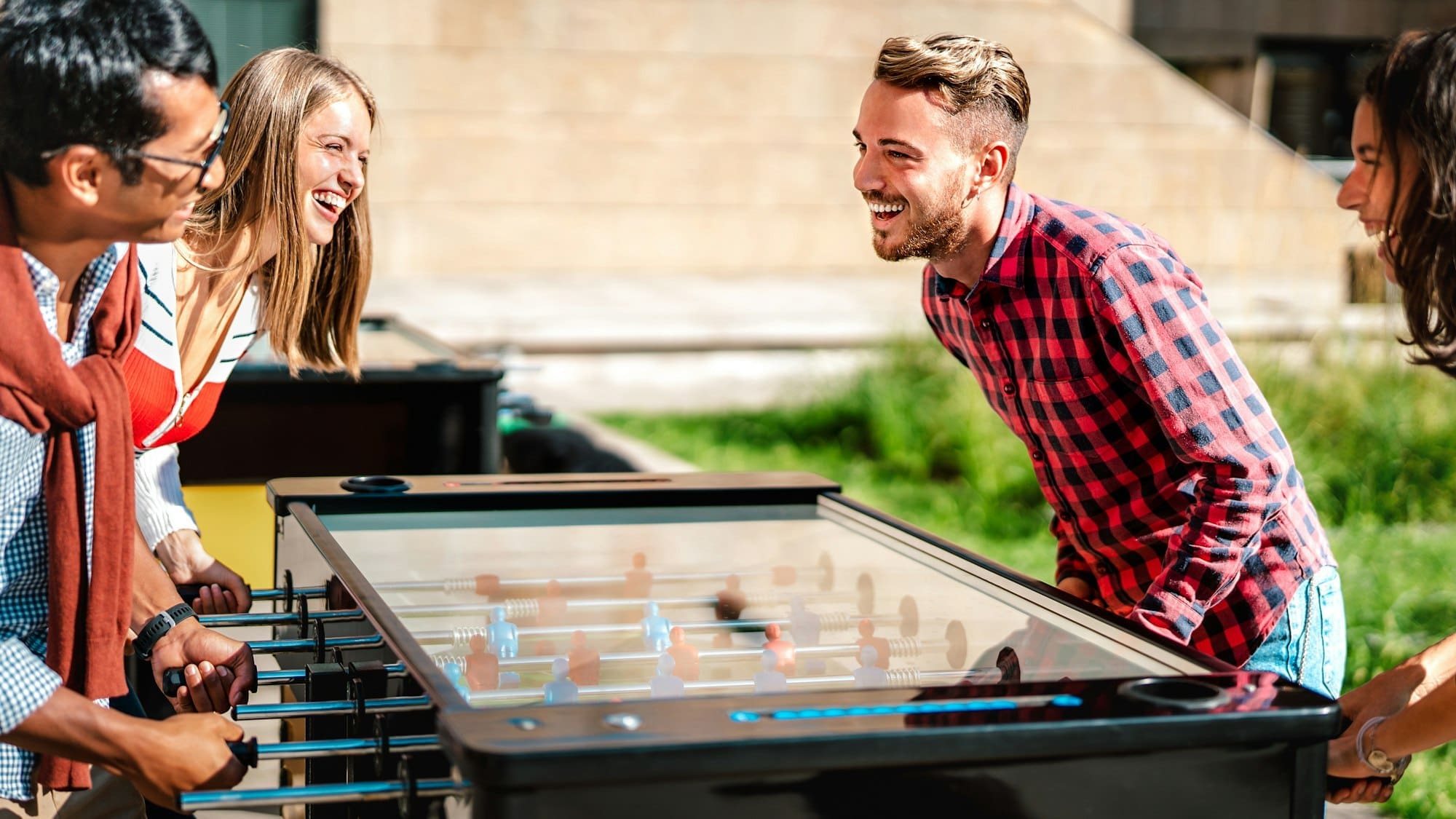 Multicultural friends play kicker table foosball at open space bar